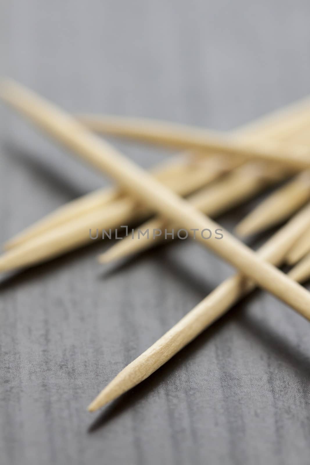 Pile of wooden toothpicks scattered randomly on a grey background for cleaning between the teeth after a meal in a personal hygiene concept