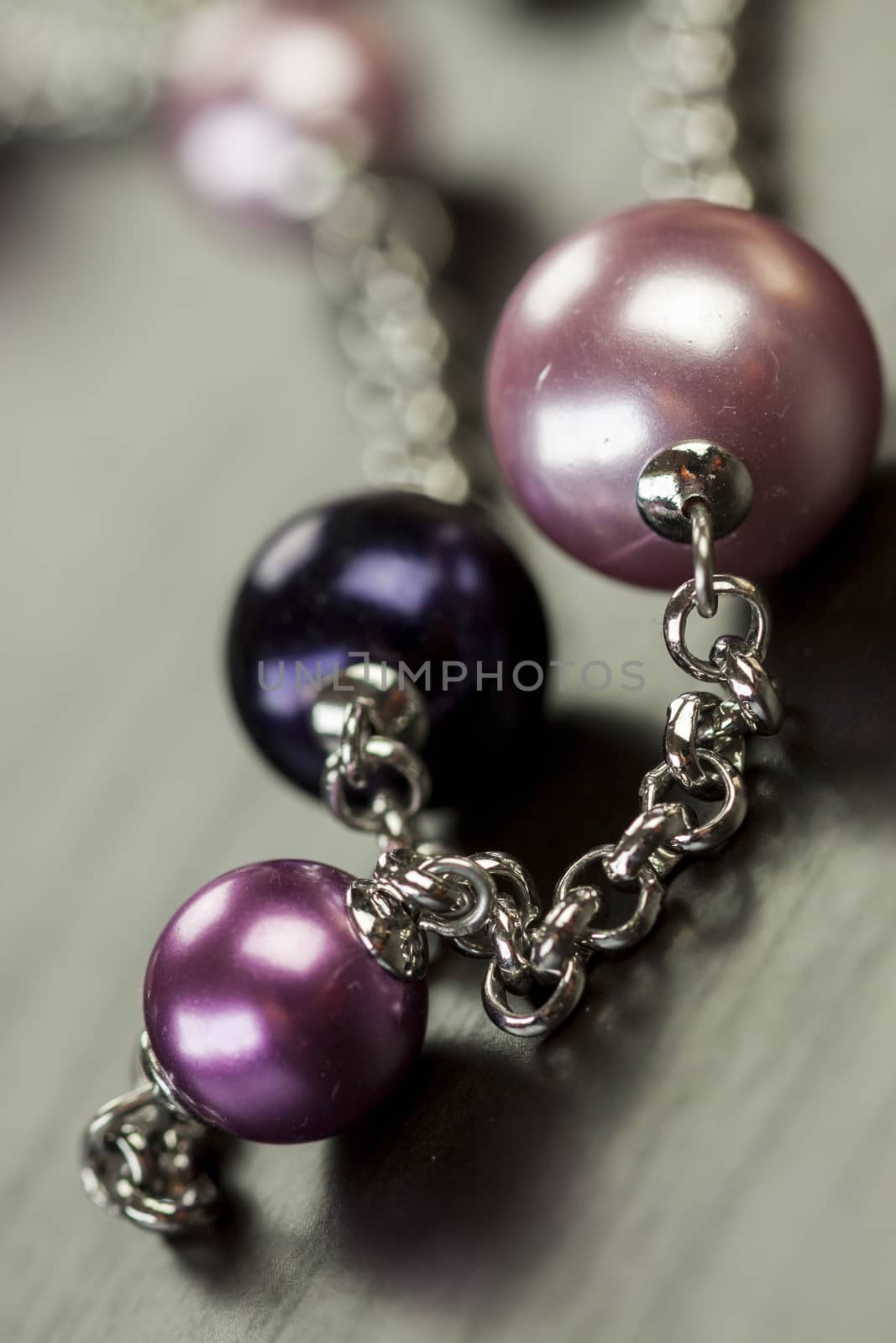 Close up of three attractive shiny purple beads attached by silver chains on an item of jewellery in a fashion and handicraft concept