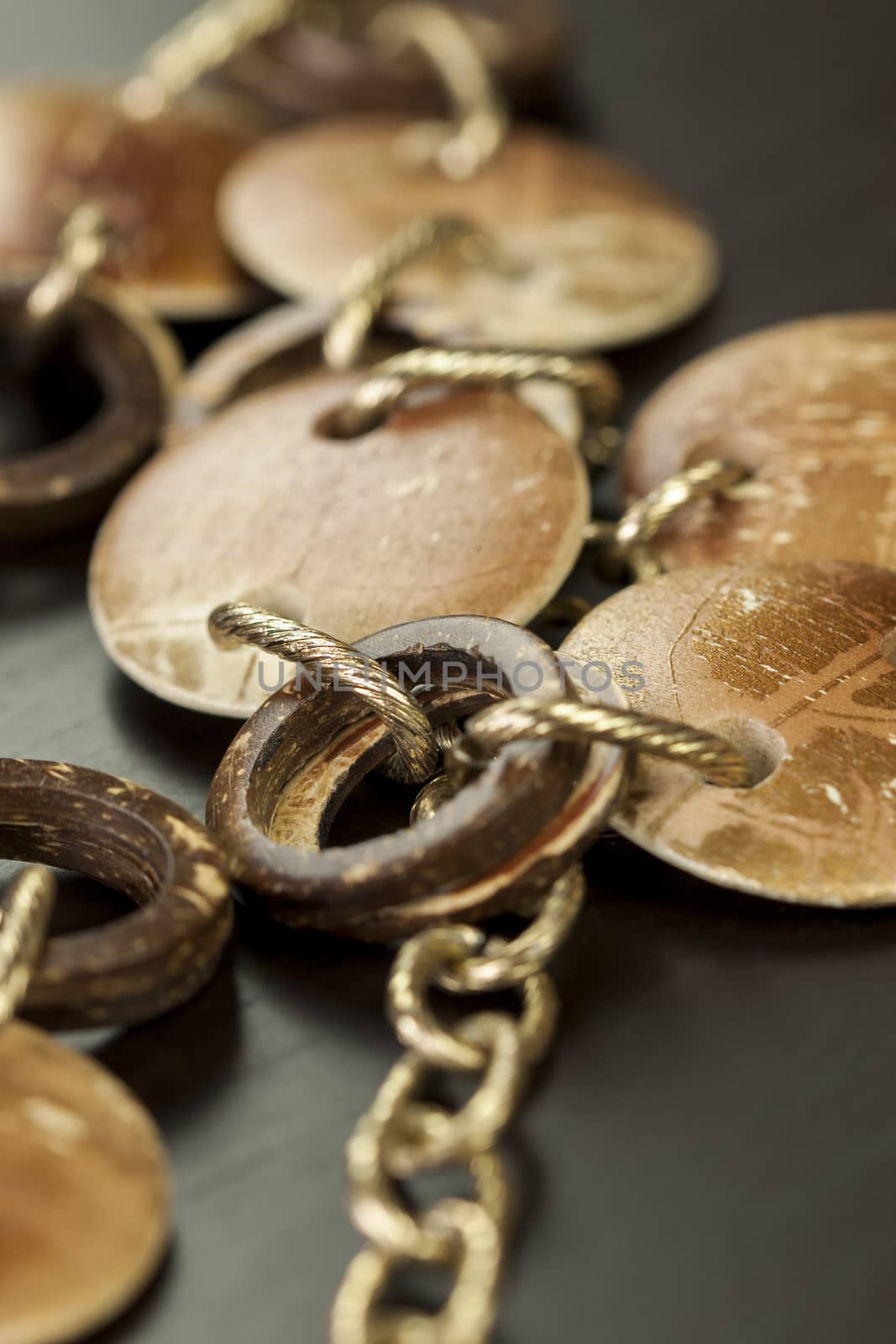 Scratched and tarnished old silver jewellery with two flat discs flanking a ring suspended on an oval link chain, close up view on a grey background