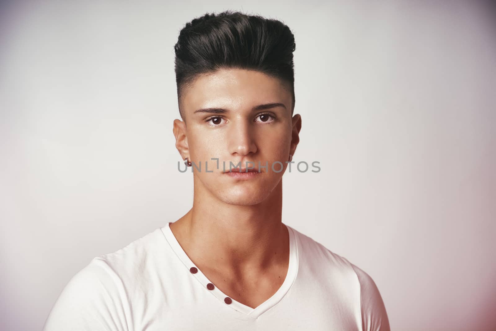 Head and shoulders portrait of handsome young man on light background looking at camera