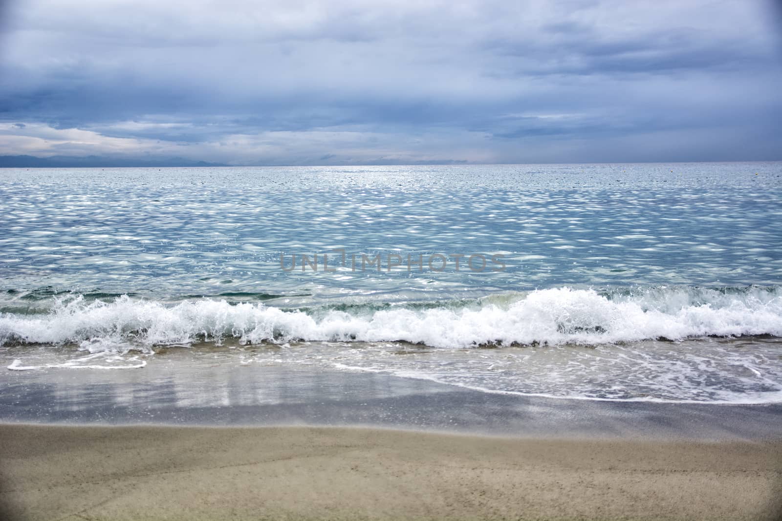 Dramatic view of sea or ocean in a cloudy day with waves and beach in foreground