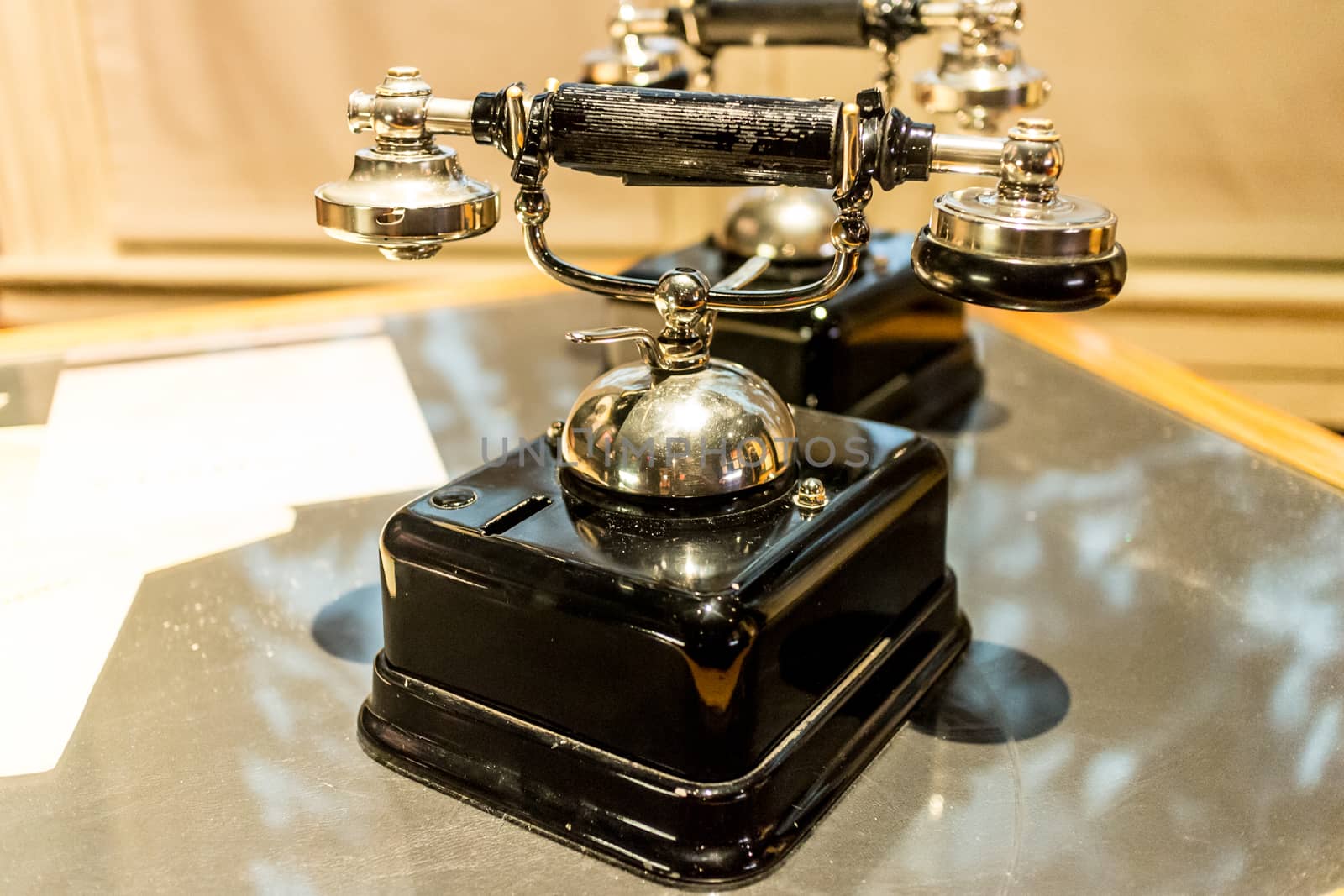 An antique analog telephone set with black box base and golden ringer, and handset