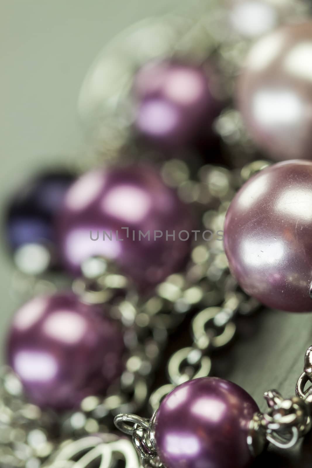 Close up of three attractive shiny purple beads attached by silver chains on an item of jewellery in a fashion and handicraft concept