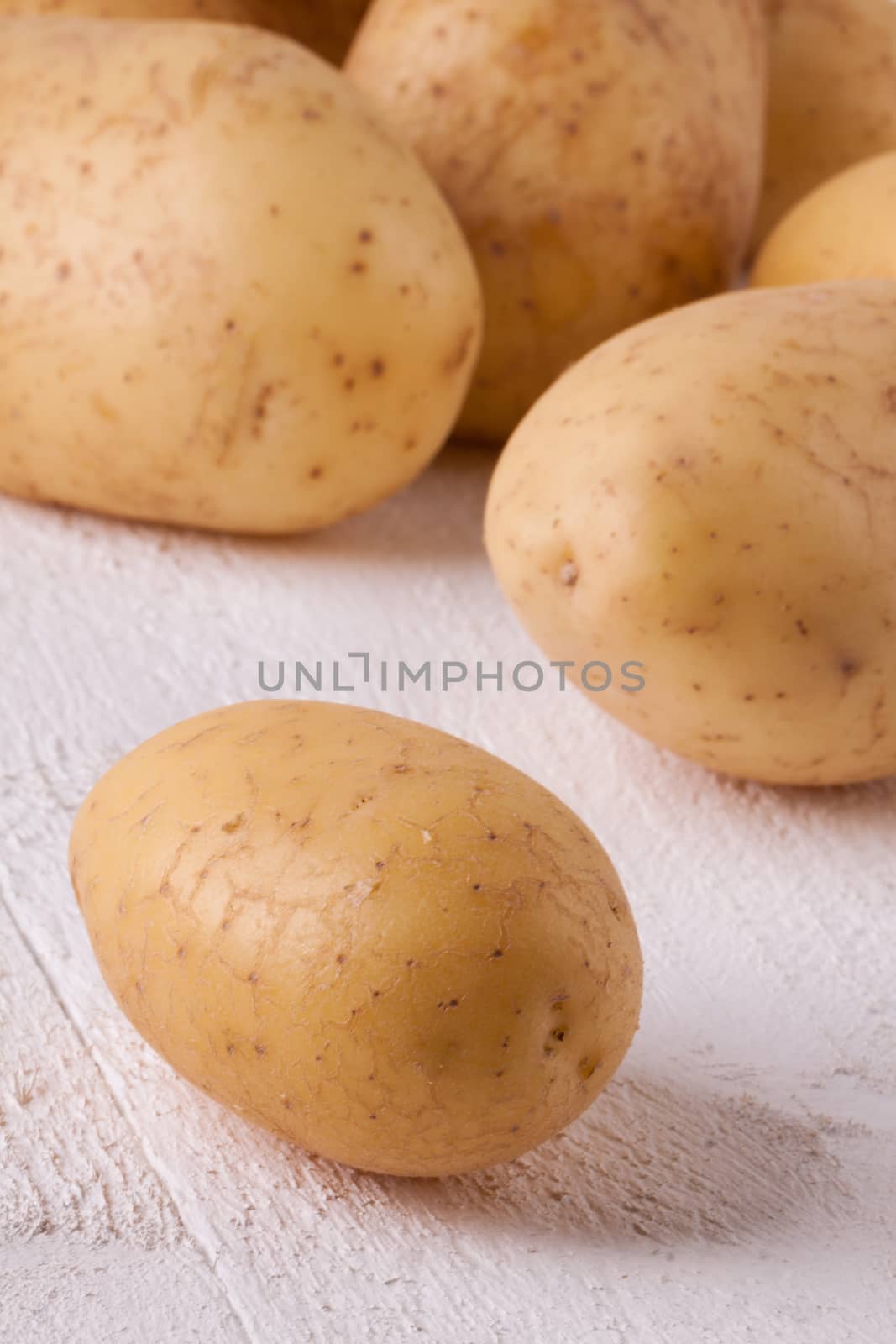 Farm fresh washed whole potatoes for a healthy nutritious cooking ingredient on white painted wooden boards