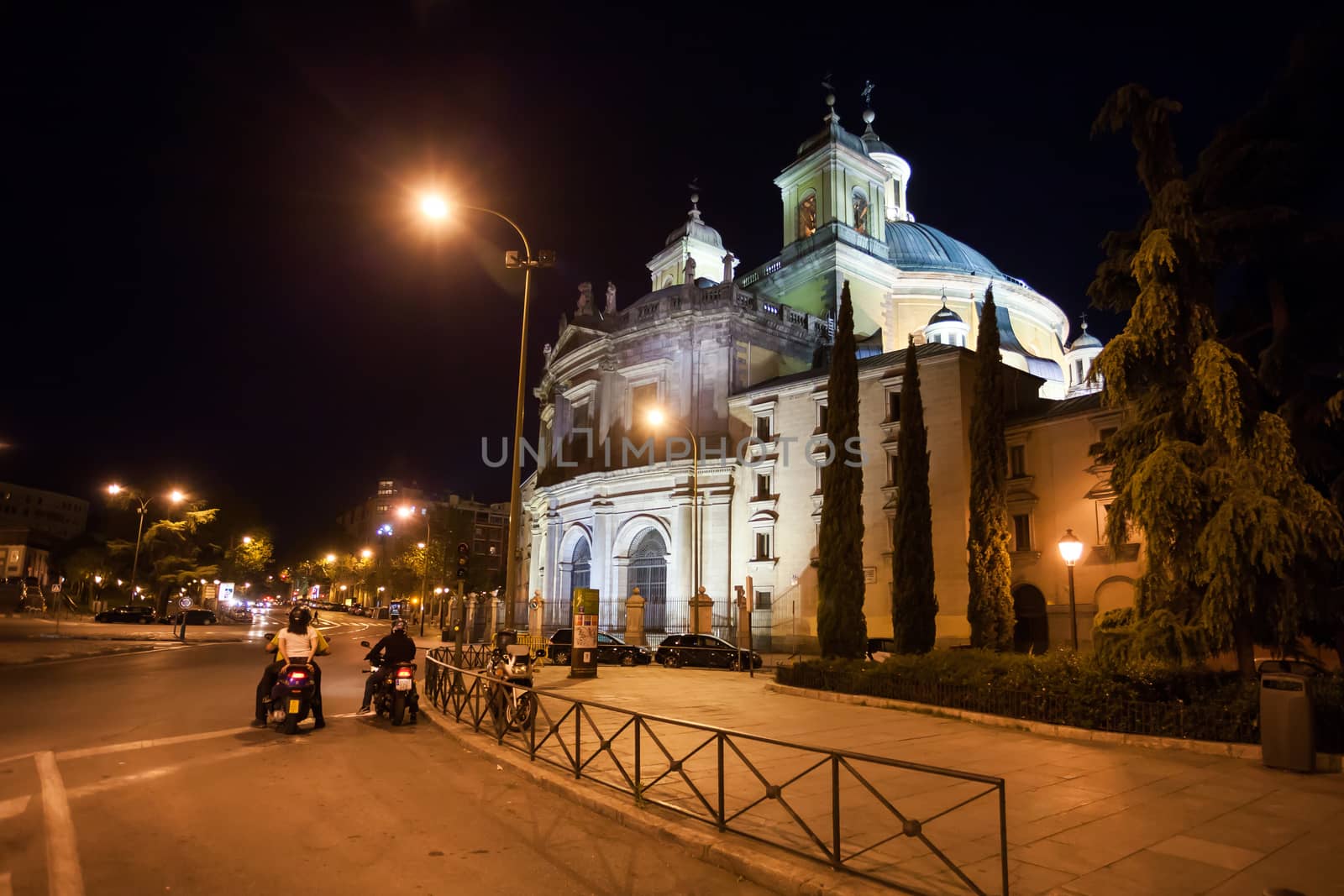 Madrid, Spain - May 6, 2012:  Side view of the Real Basilica de San Francisco el Grande on a sunny spring night and moped bikers on street, Madrid, Spain