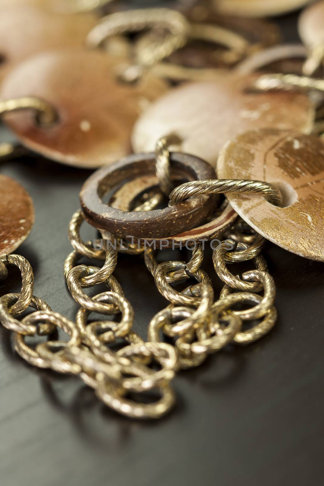 Scratched and tarnished old silver jewellery with two flat discs flanking a ring suspended on an oval link chain, close up view on a grey background