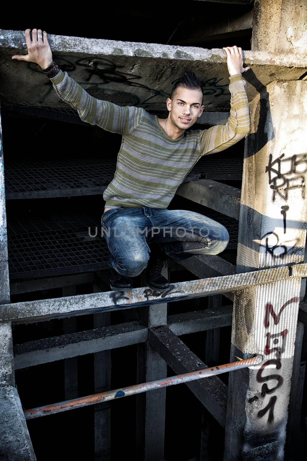 Handsome smiling young man in abandoned industrial site outdoor looking at camera