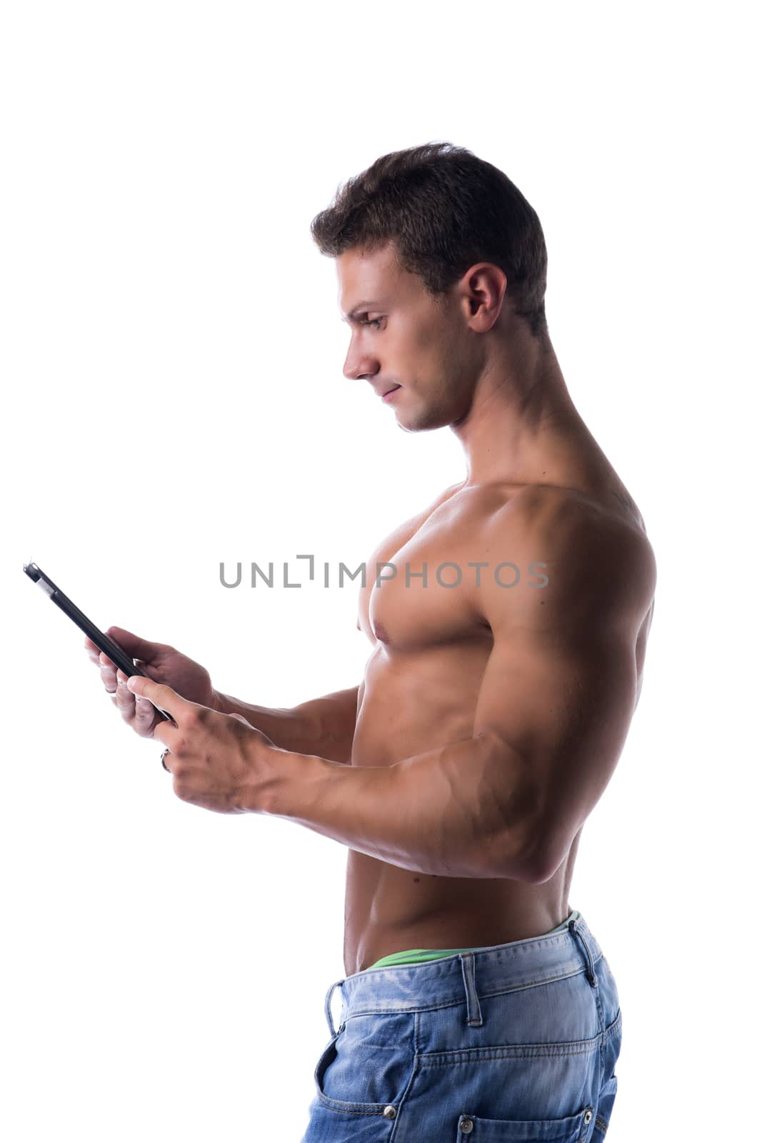 Shirtless young male bodybuiler holding ebook reader or tablet PC standing isolated on white background