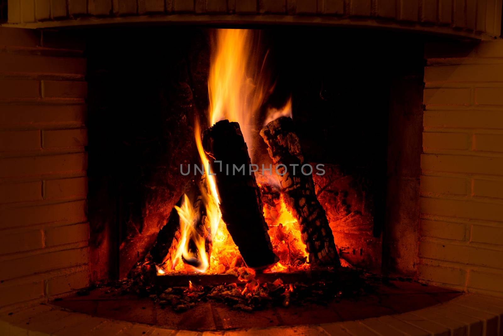 Burning fireplace with firewood and glowing ashes