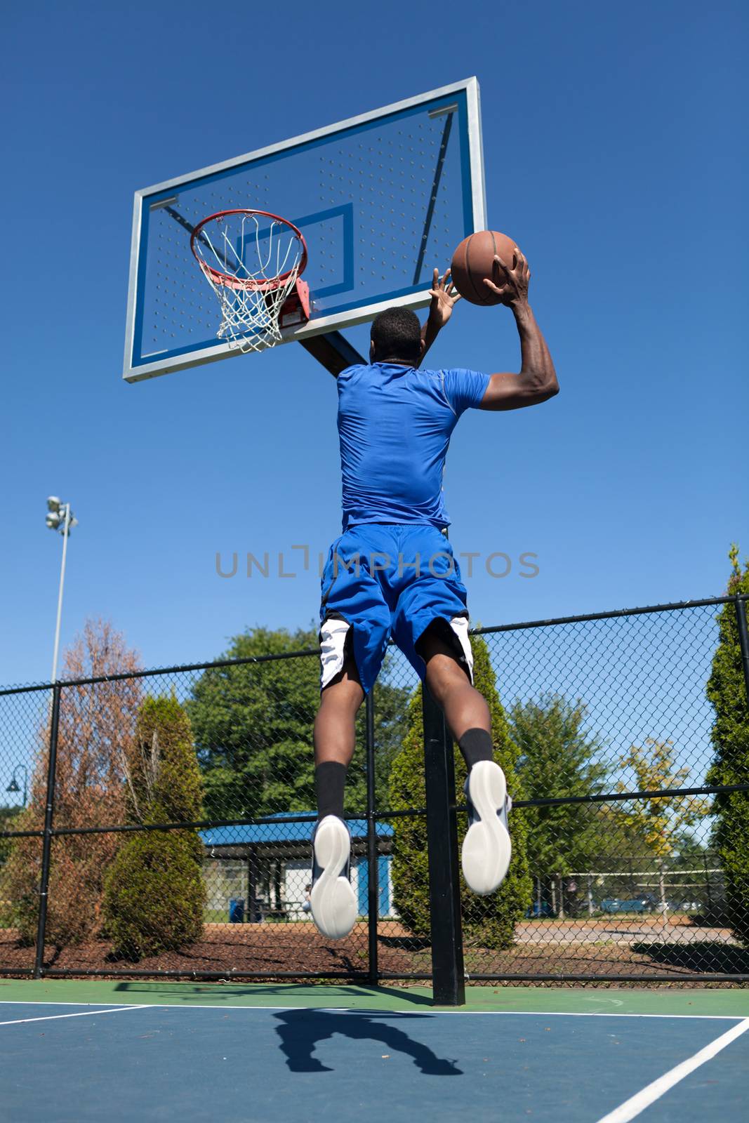 Young basketball player driving to the hoop for a high flying slam dunk.