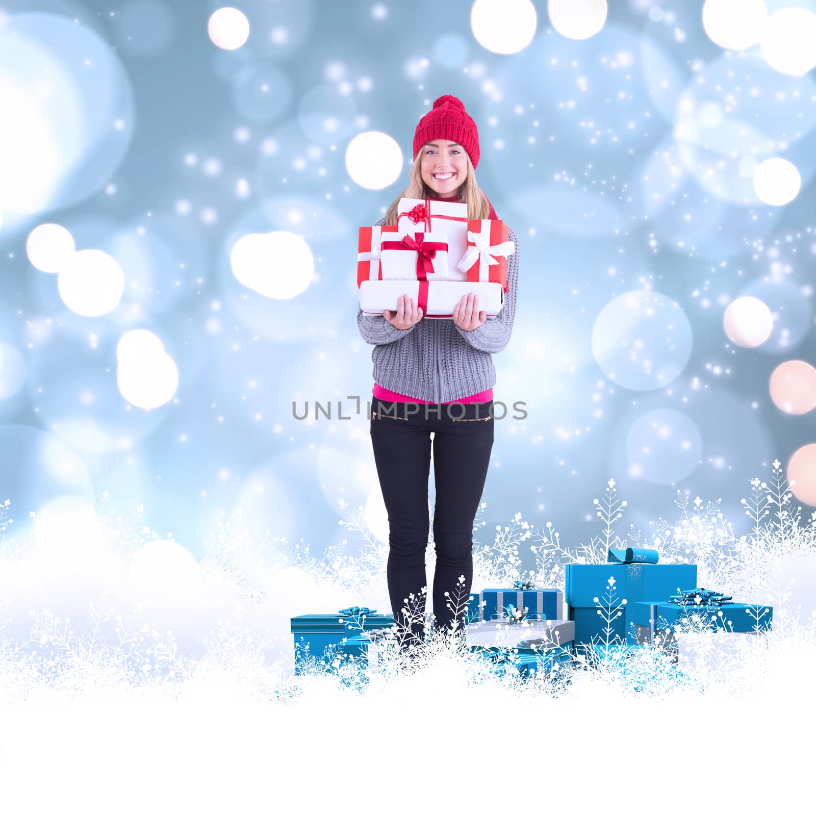 Festive blonde holding pile of gifts against white glowing dots on blue