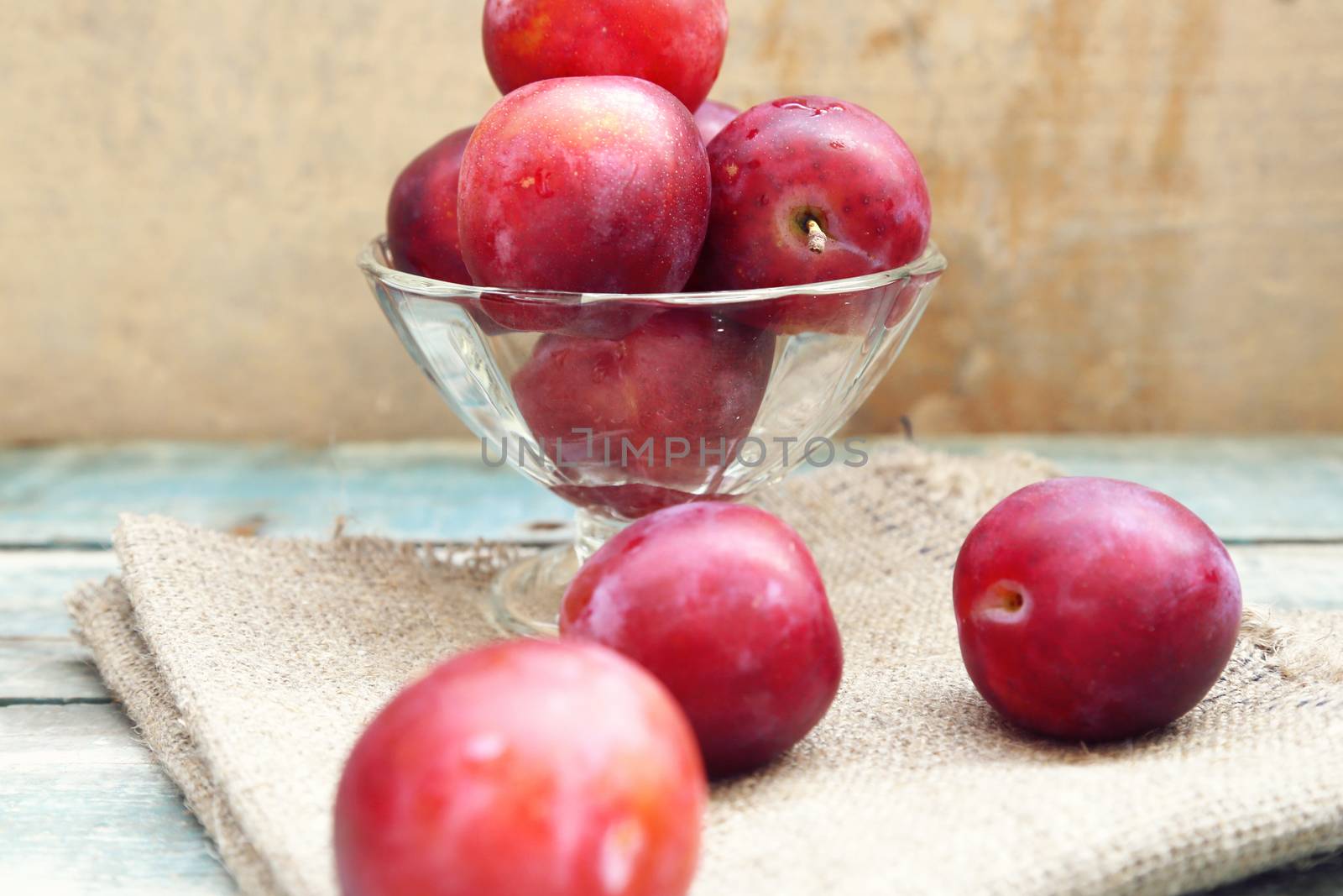 fresh, moist, ripe plums are in a transparent bowl