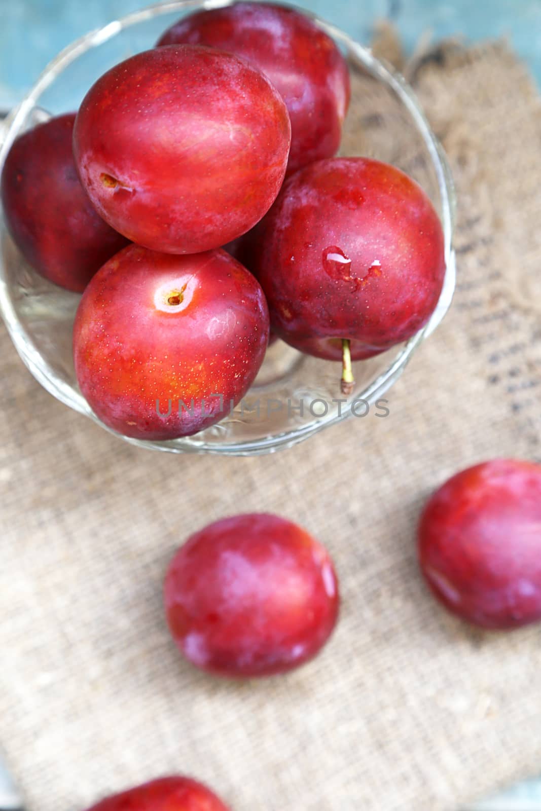 fresh, moist, ripe plums are in a transparent bowl