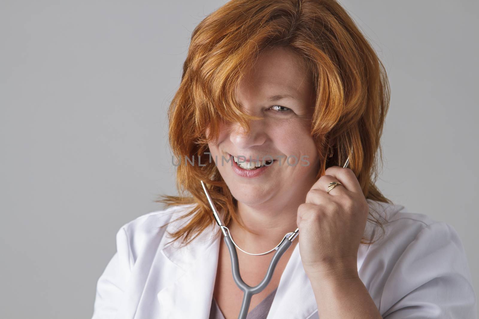 Woman in her early fortie wearing a lab coat and putting a stethoscope in her ears