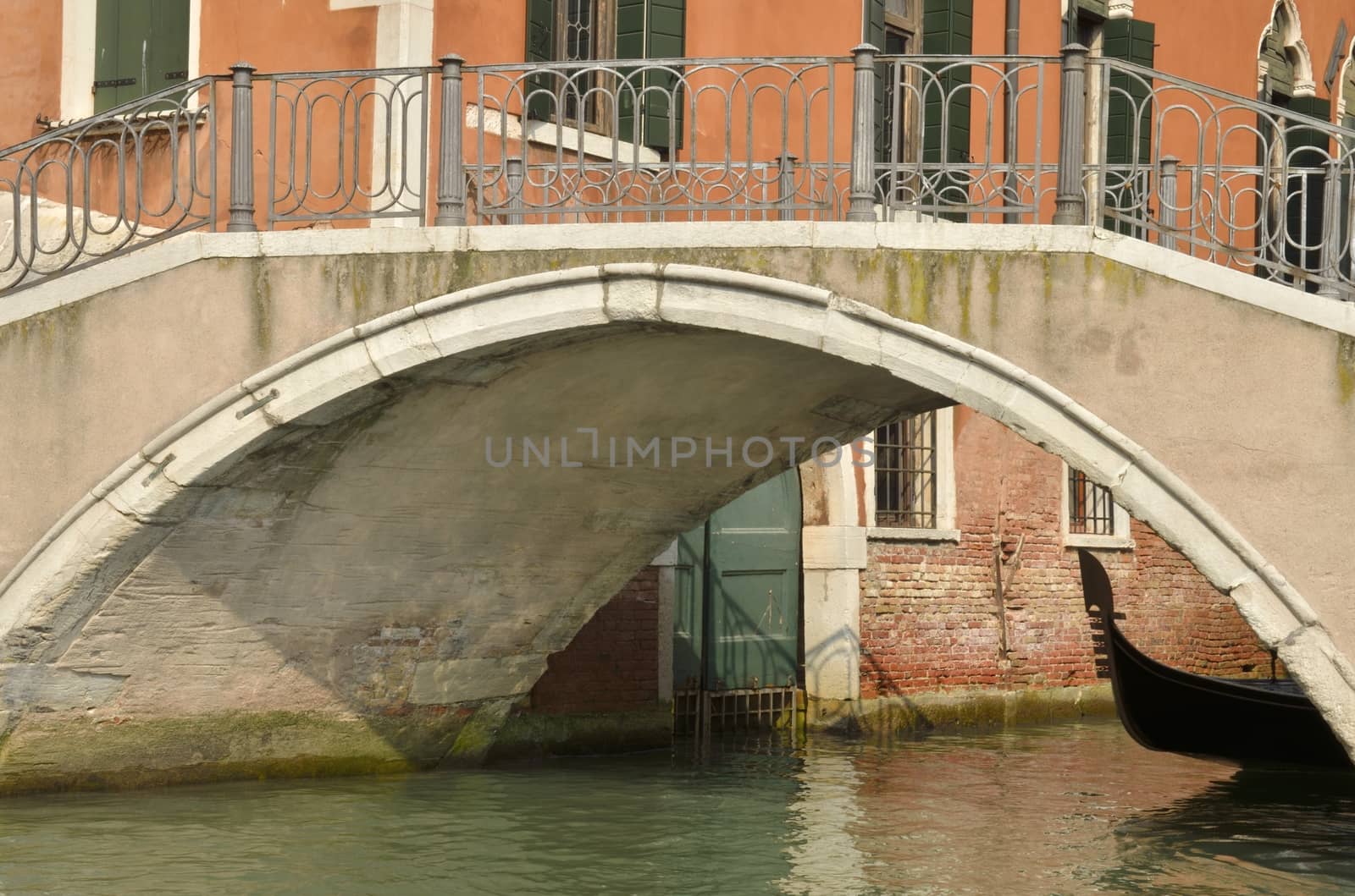 Gondola passing under a bridge in a canal in Venice, Italy.
