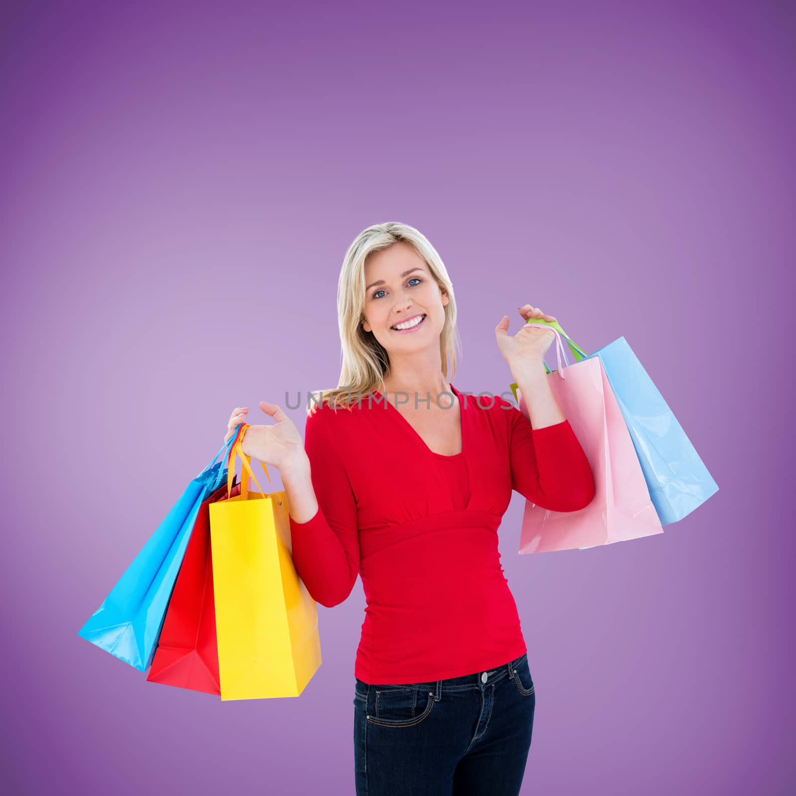 Happy blonde holding shopping bags against purple vignette