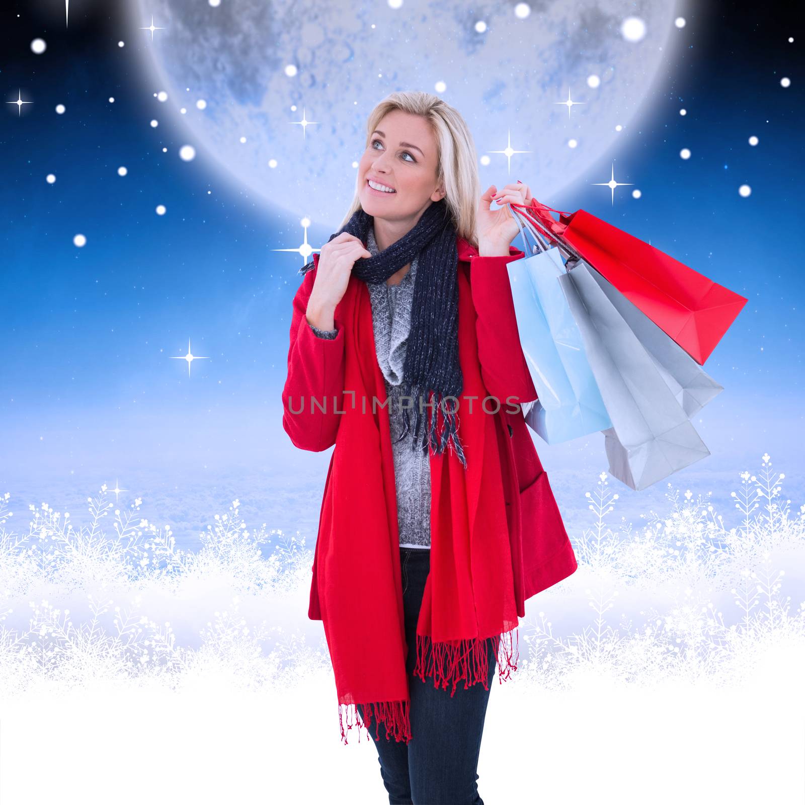 Blonde in winter clothes holding shopping bags against white clouds under blue sky