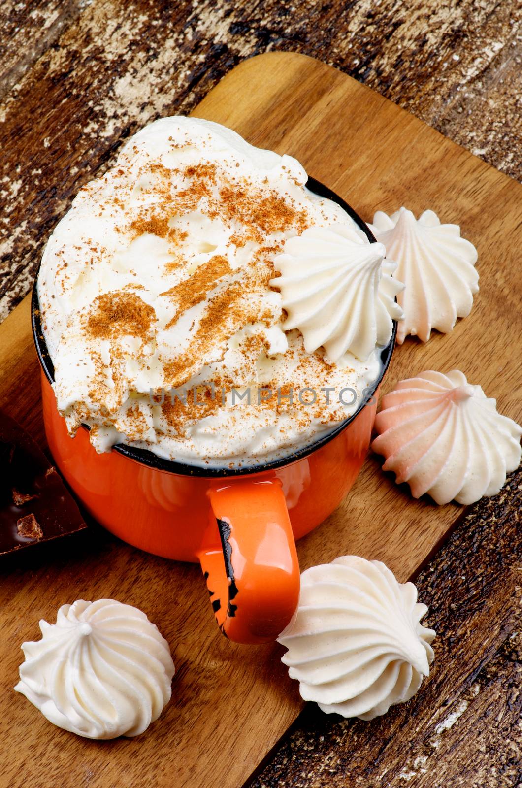 Cup of Hot Chocolate with Whipped Cream, Cinnamon  and Meringues on Cutting Board on Rustic Wooden background. Top View