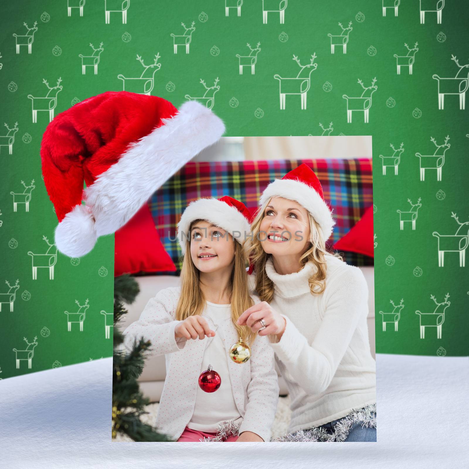 Festive mother and daughter decorating christmas tree against green reindeer pattern