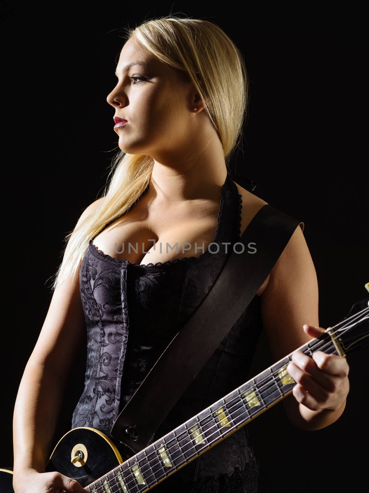 Photo of a sexy blond female playing a black electric guitar wearing a black corset.
