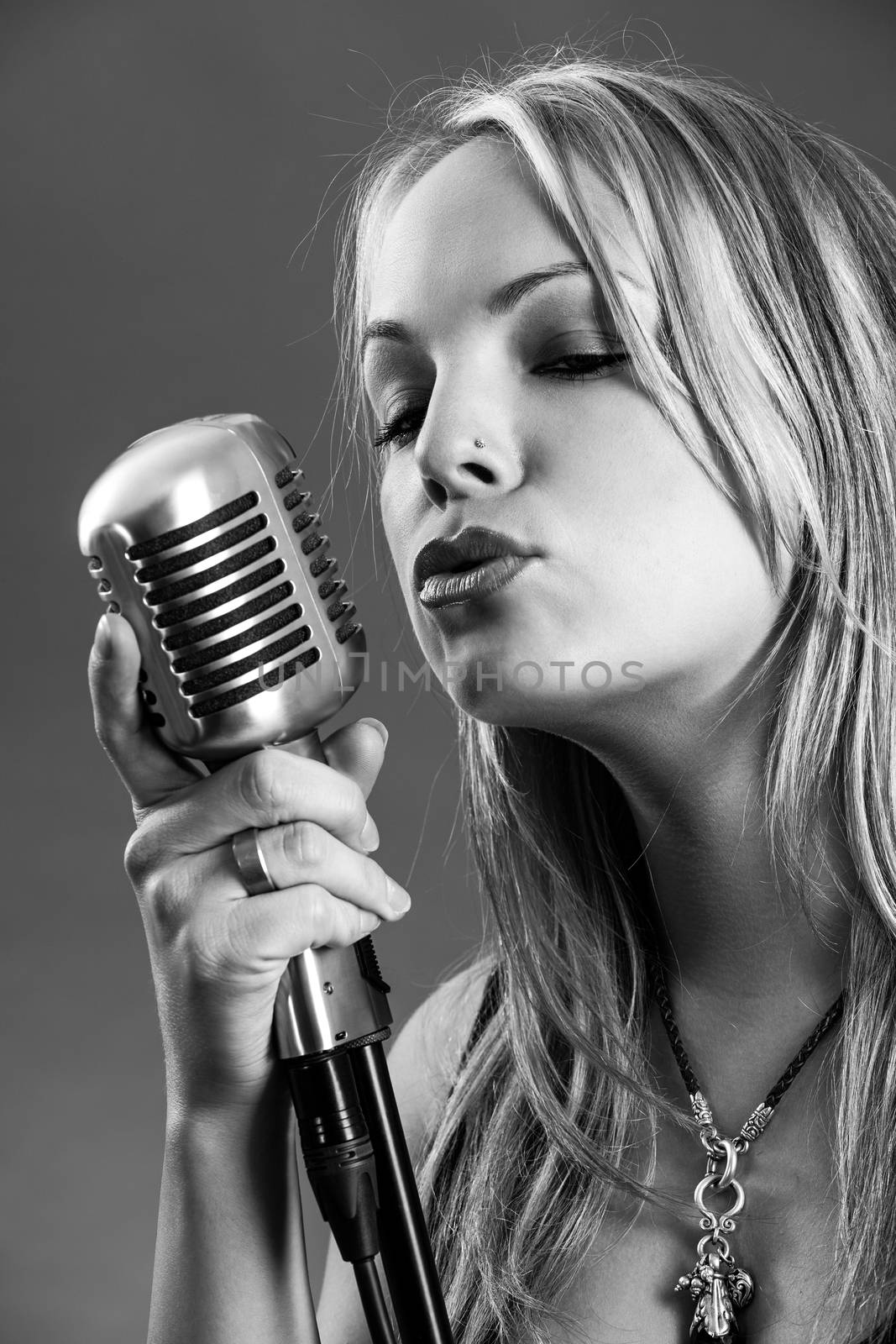 Blond singing with vintage microphone by sumners