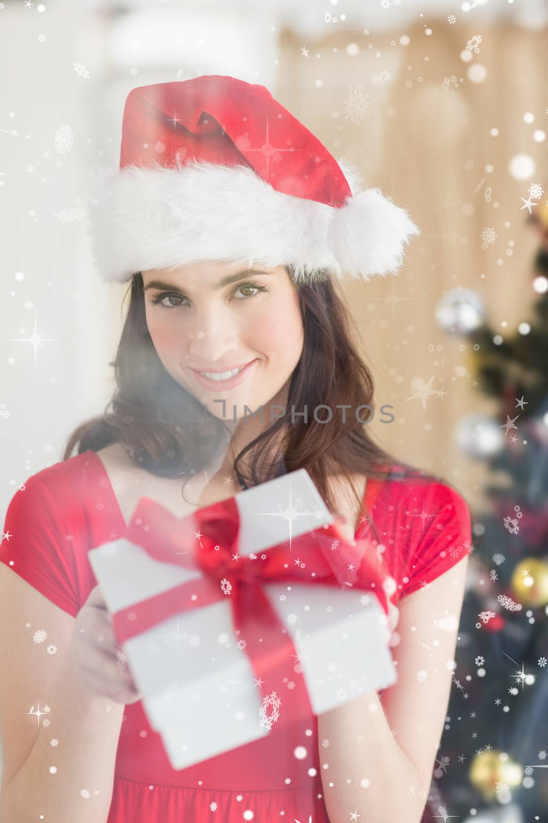Beauty brunette showing gift at christmas against snow falling