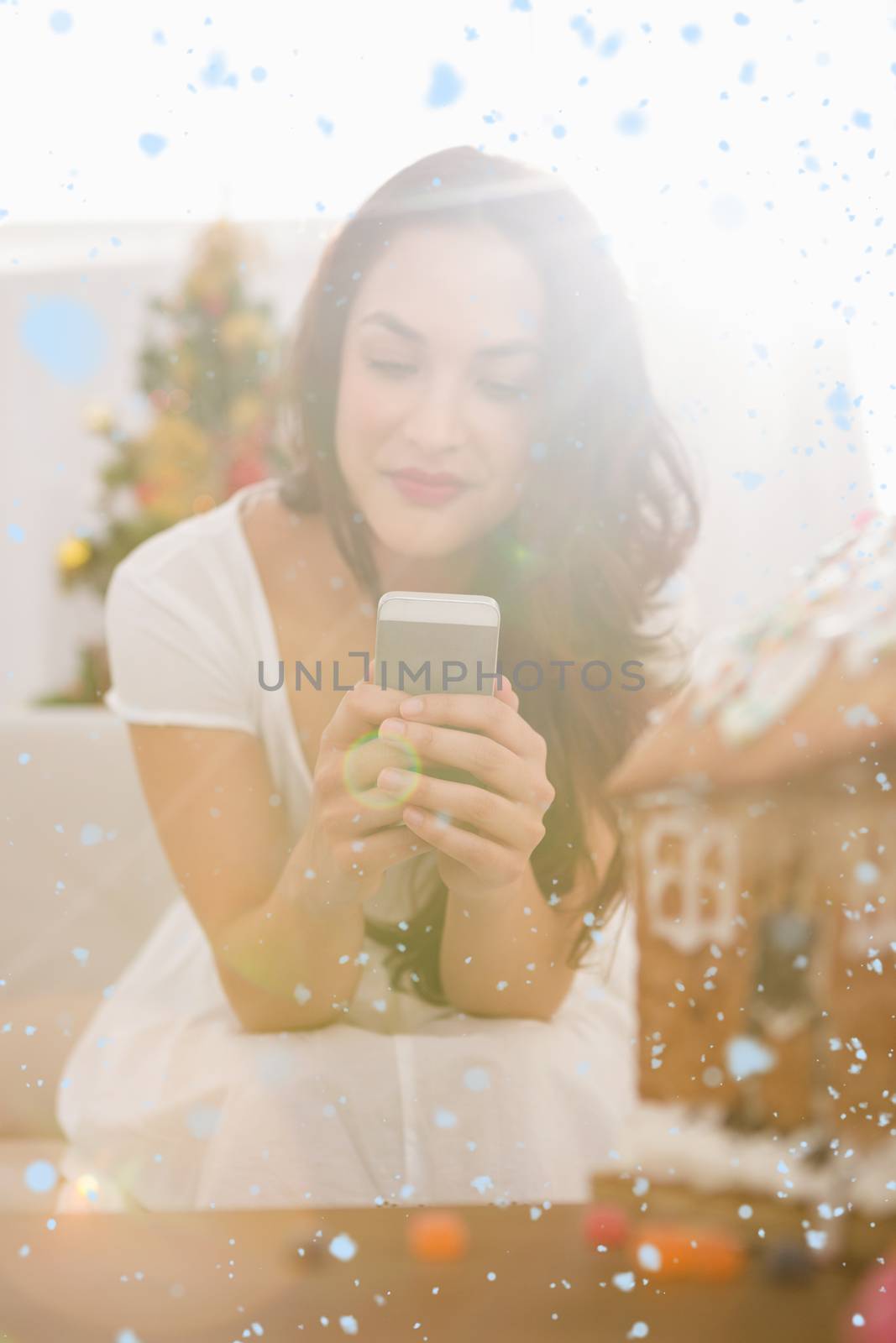 Beauty brunette using her smartphone on the sofa against snow falling