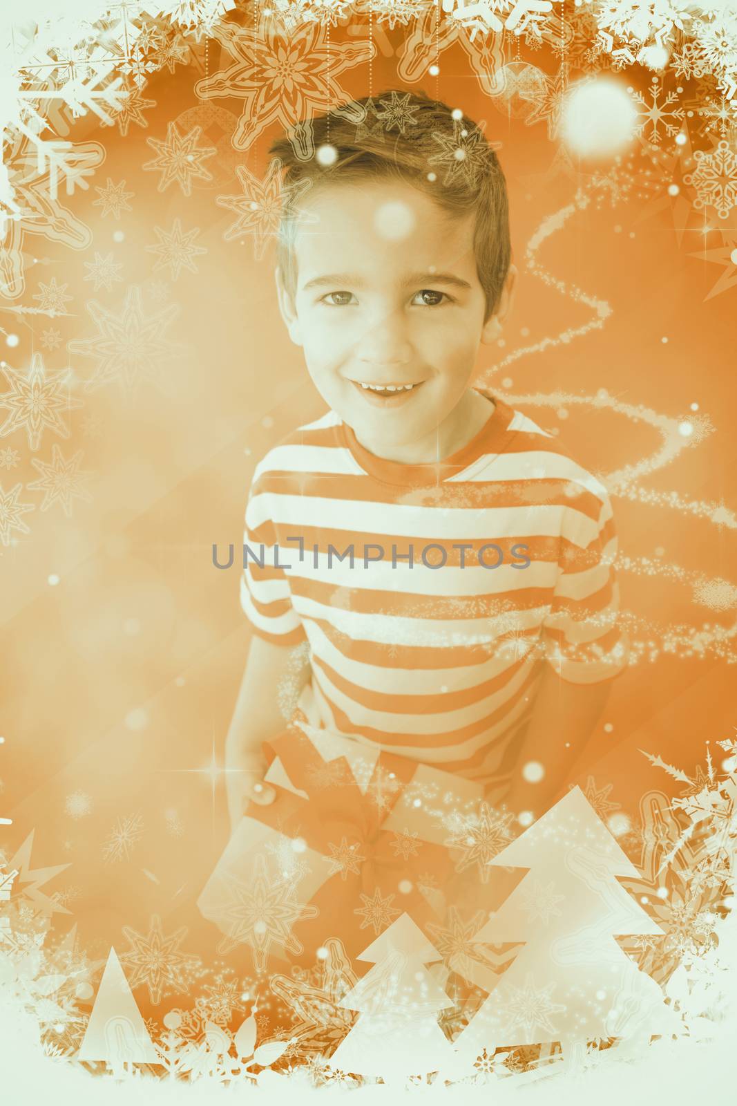 Festive little boy holding a gift against glittering christmas tree design