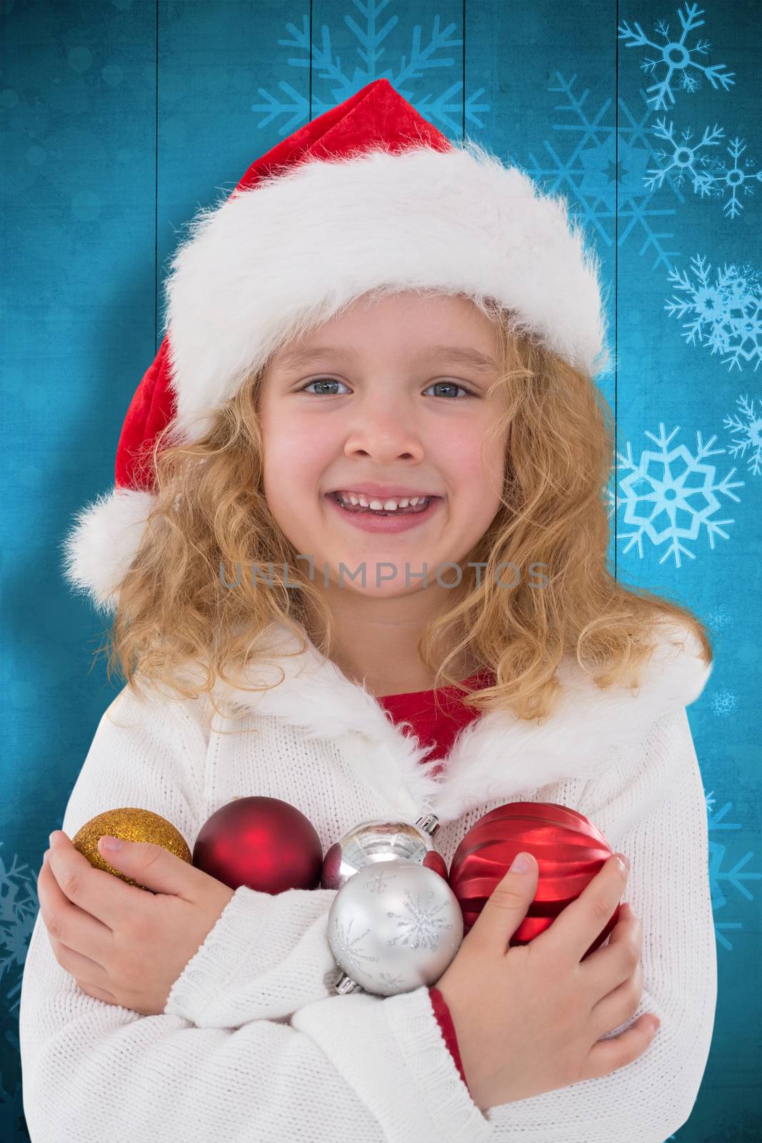 Festive little girl smiling at camera against snowflake pattern on blue planks