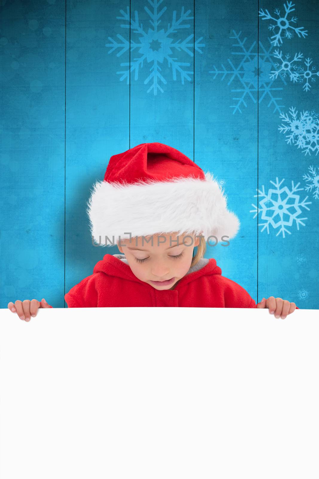 Festive little girl showing poster against snowflake pattern on blue planks