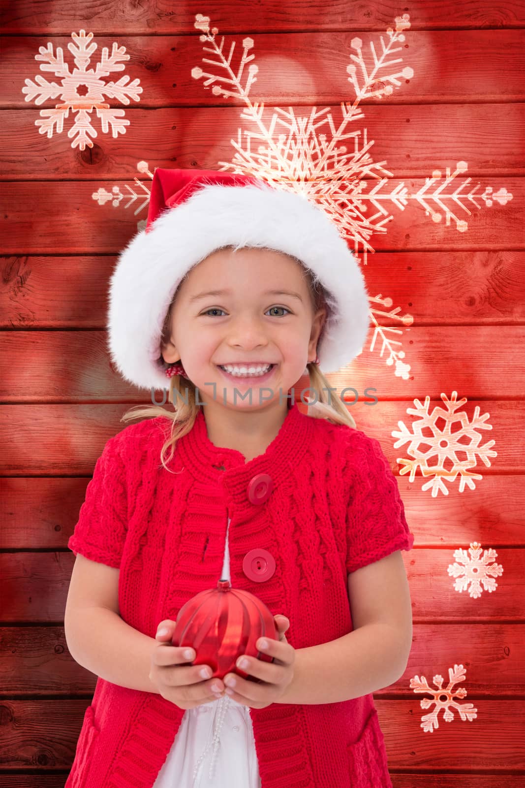 Composite image of cute little girl wearing santa hat holding bauble by Wavebreakmedia