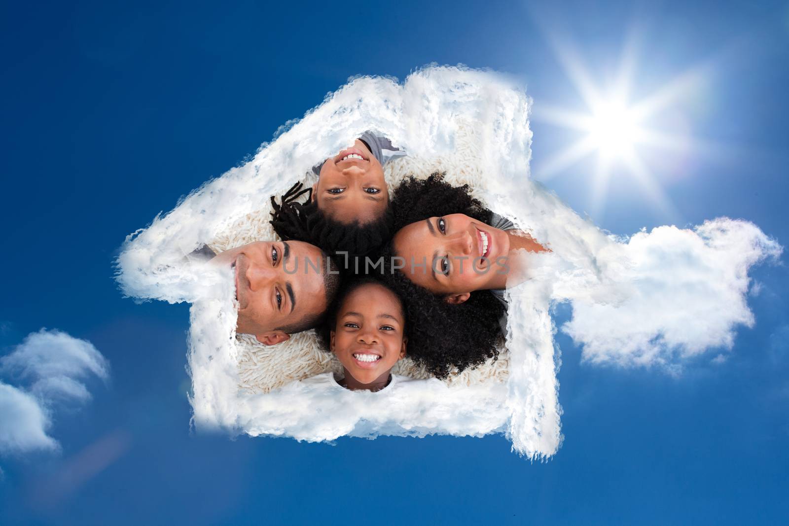Family on floor with heads together against bright blue sky with clouds