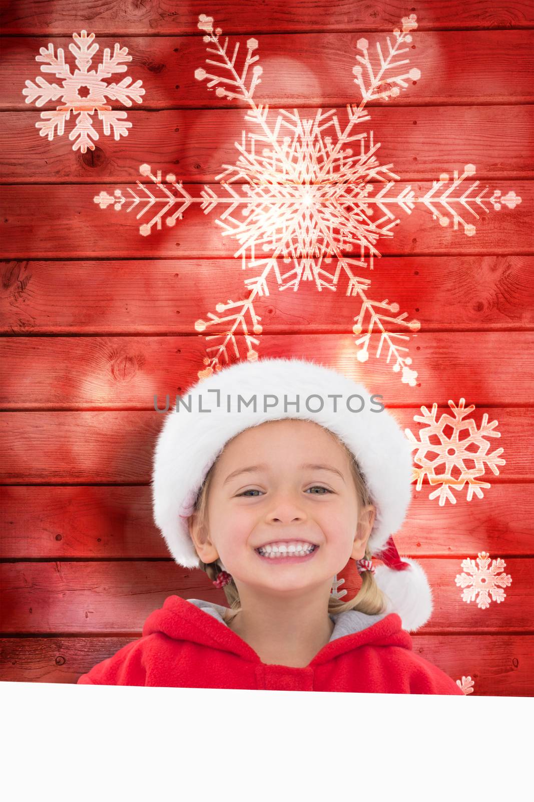 Festive little girl showing poster against snowflake pattern on red planks