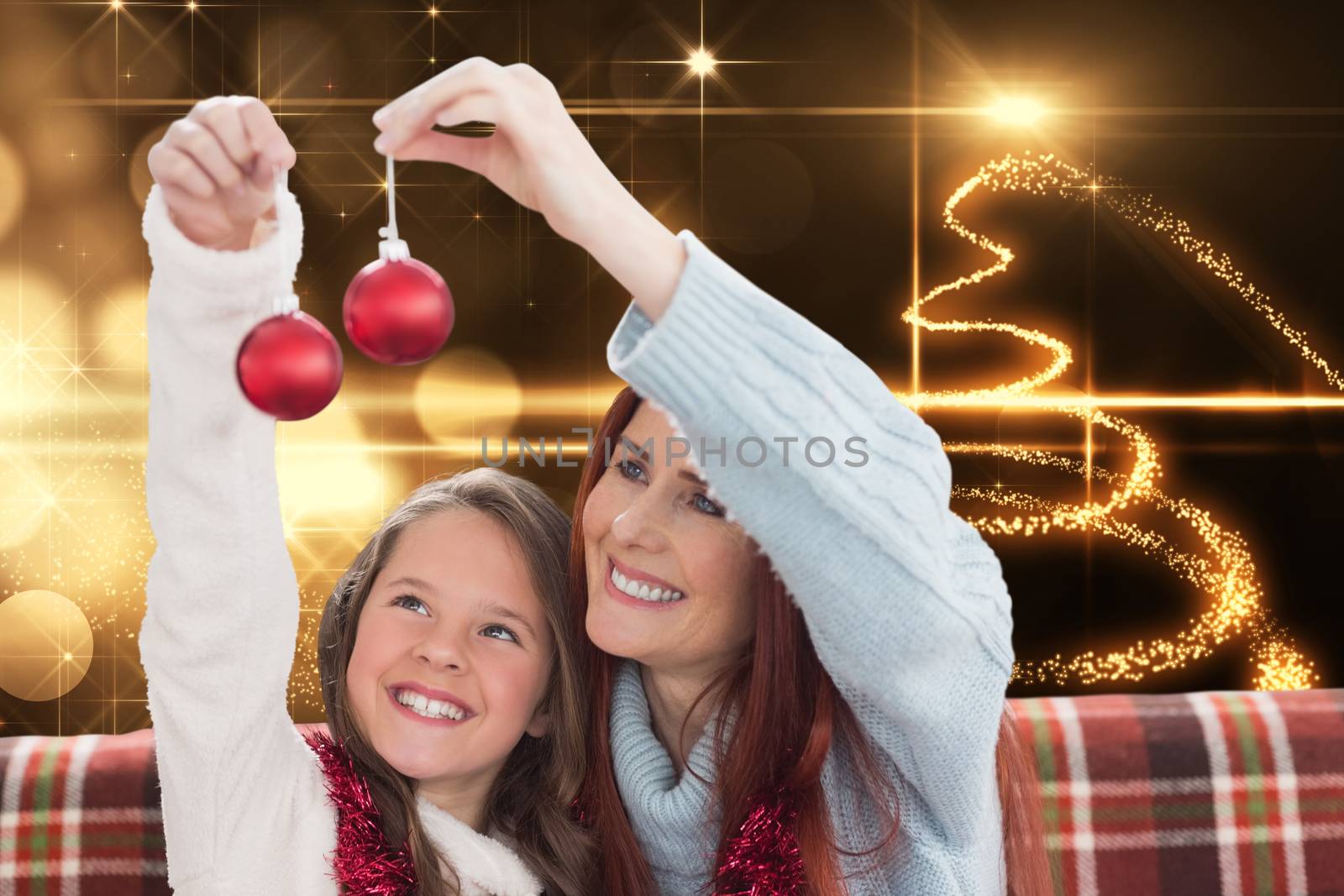 Mother and daughter holding baubles against christmas light design