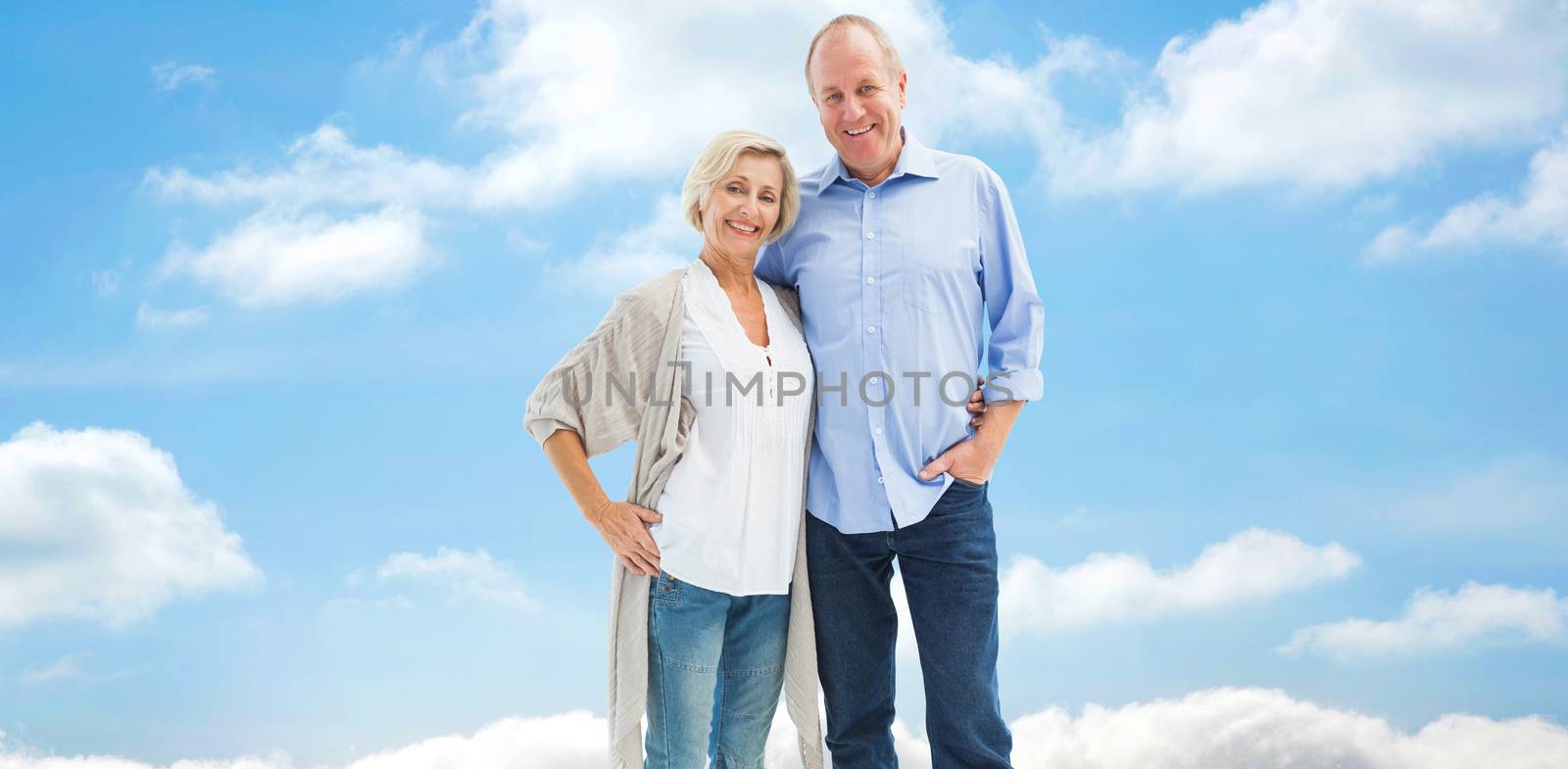 Happy mature couple hugging and smiling against cloudy sky