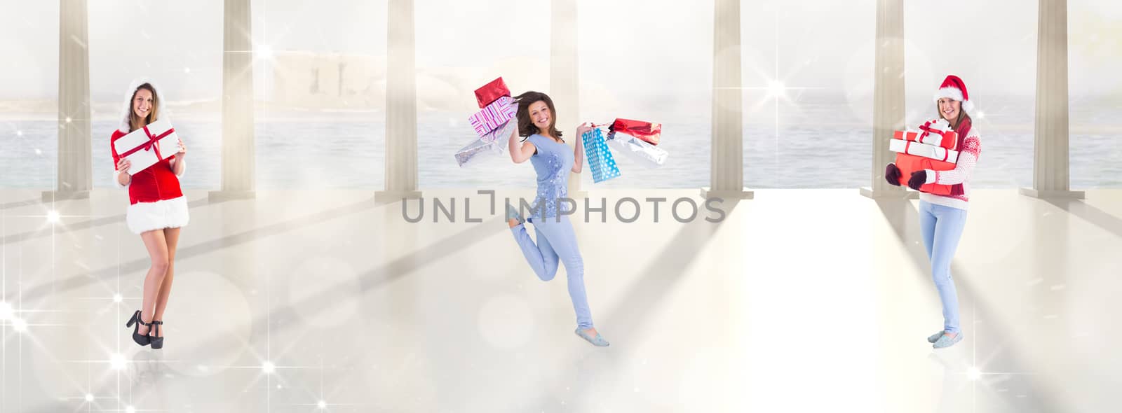 Festive brunette holding pile of gifts against twinkling lights over balcony with columns