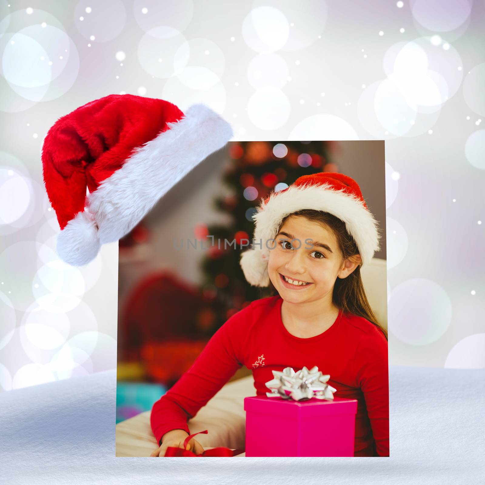 Festive little girl smiling at camera with gifts against purple abstract light spot design
