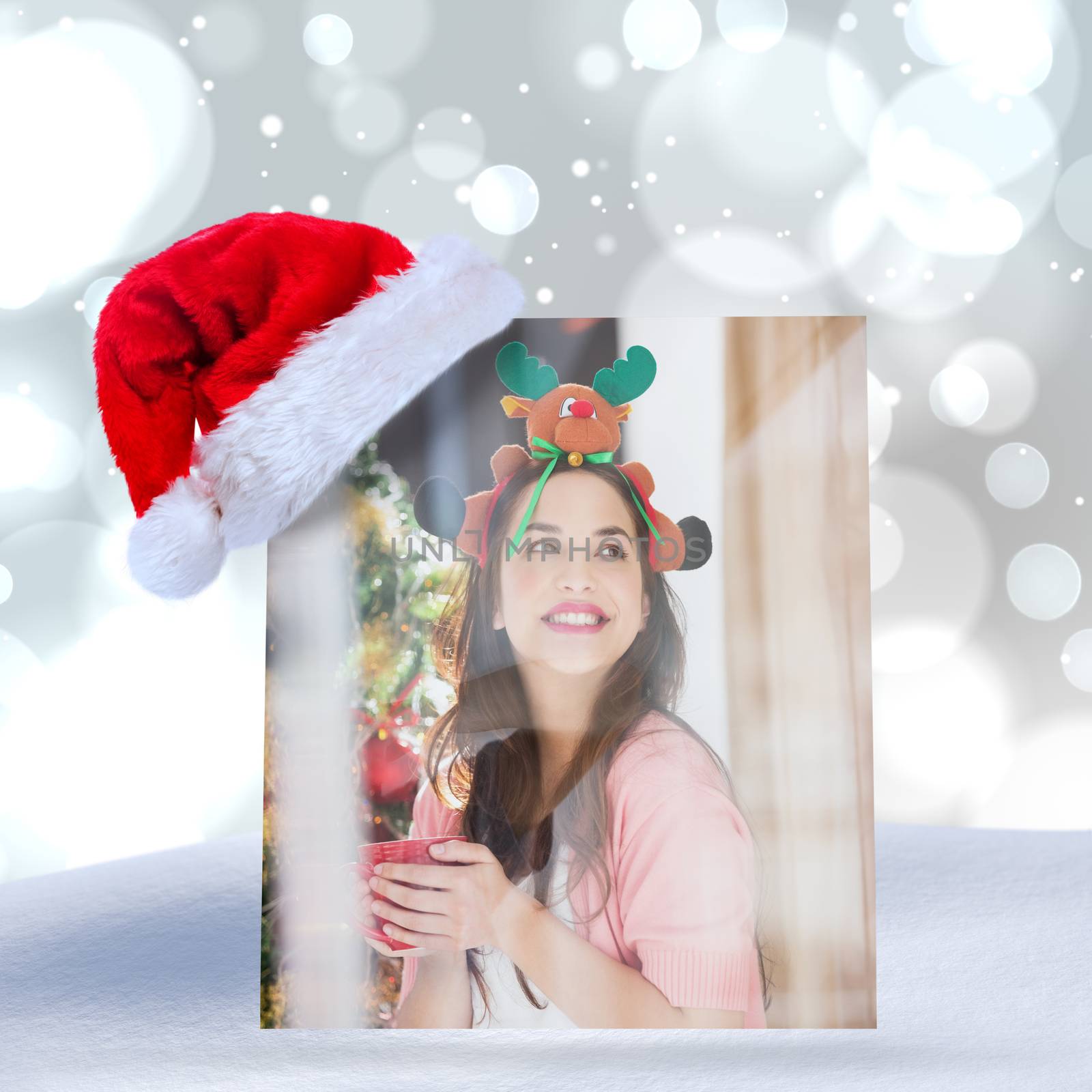 Composite image of smiling brunette in christmas hat holding mug by Wavebreakmedia