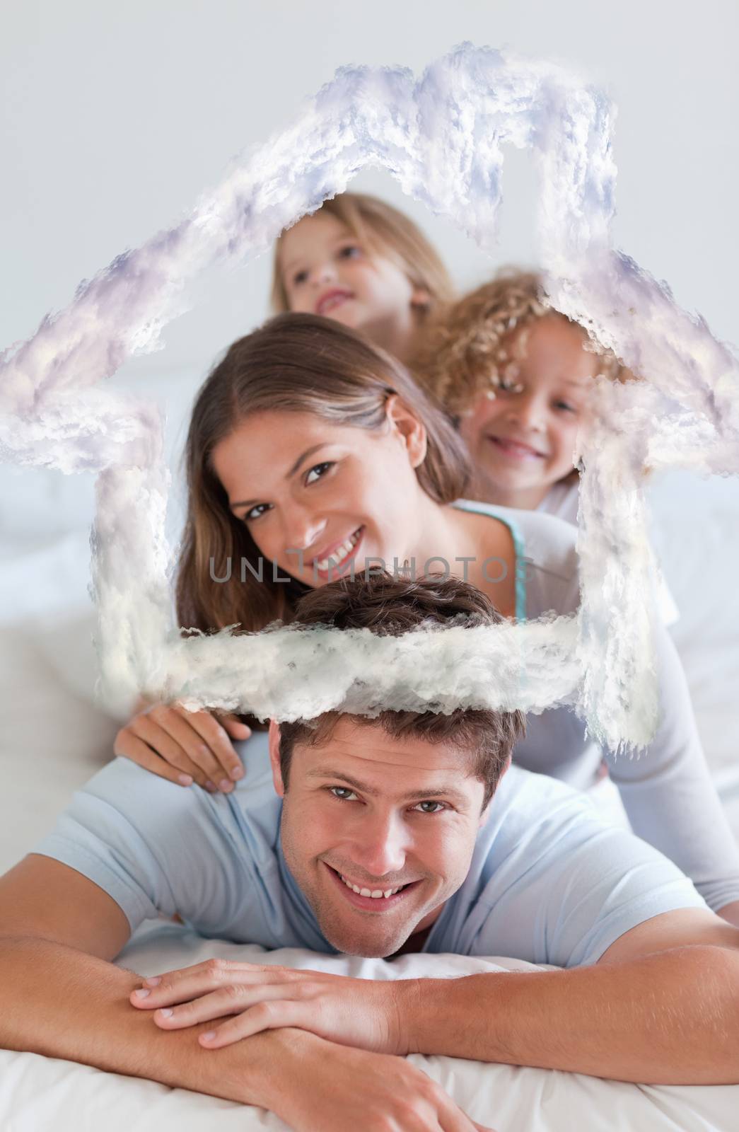 Portrait of a joyful family lying on each other against house outline in clouds