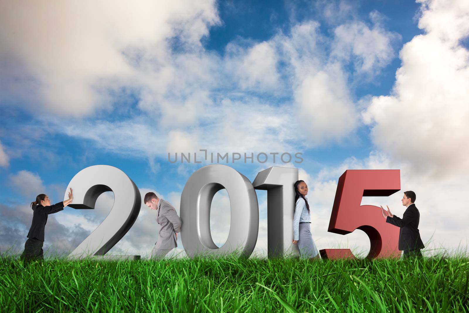 Businessman in suit pushing against green grass under blue sky