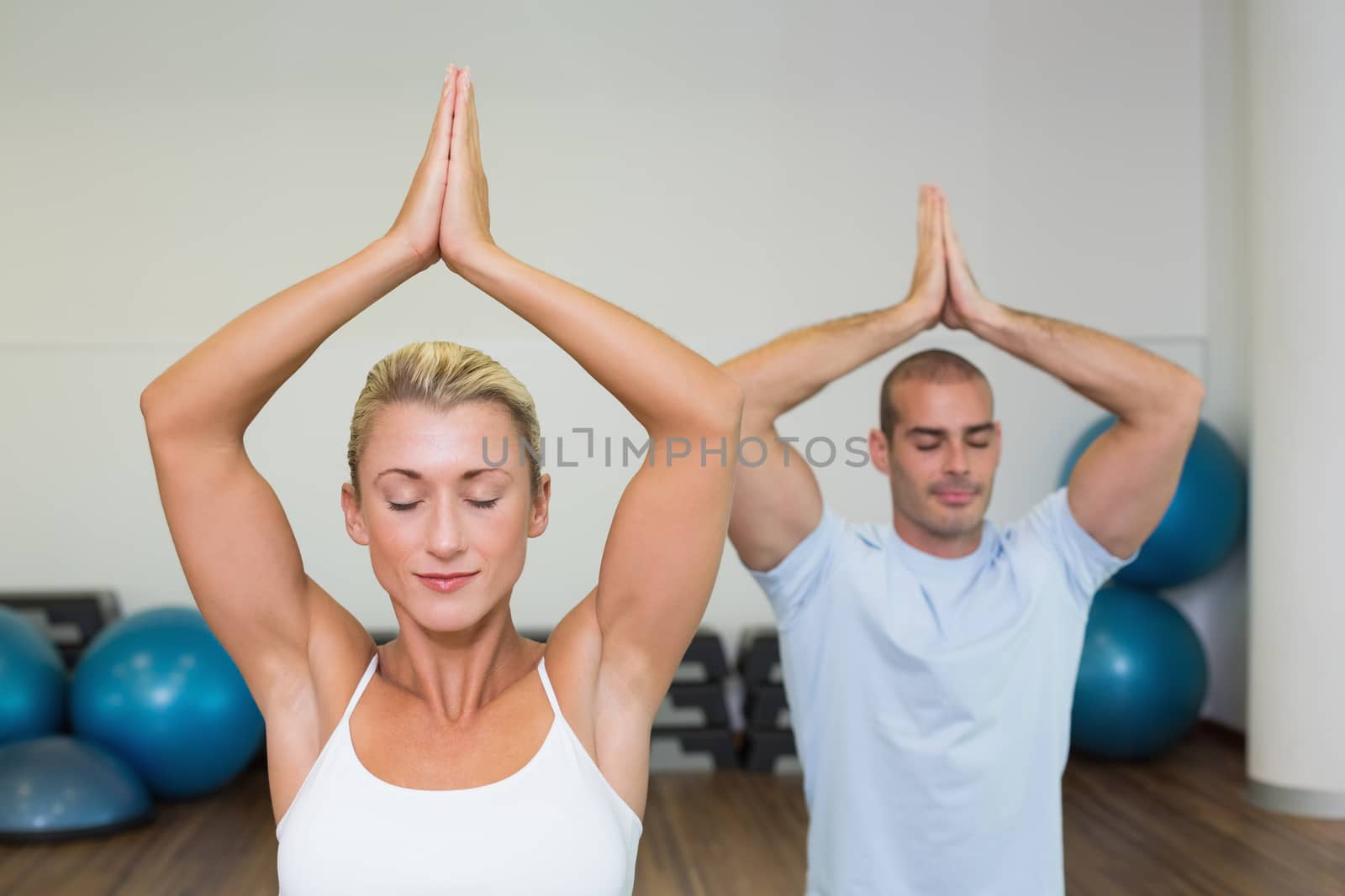 Couple with joined hands and eyes closed at fitness studio by Wavebreakmedia