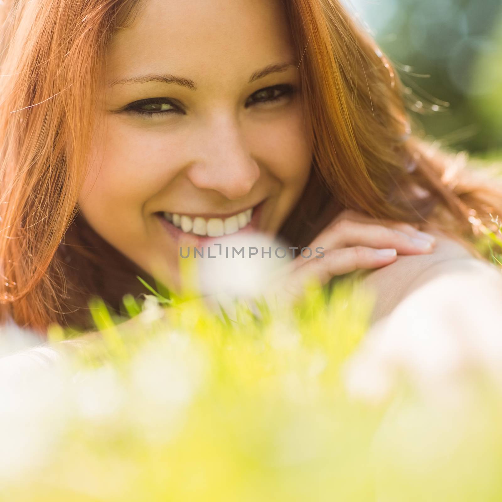 Portrait of a pretty redhead content and lying on grass