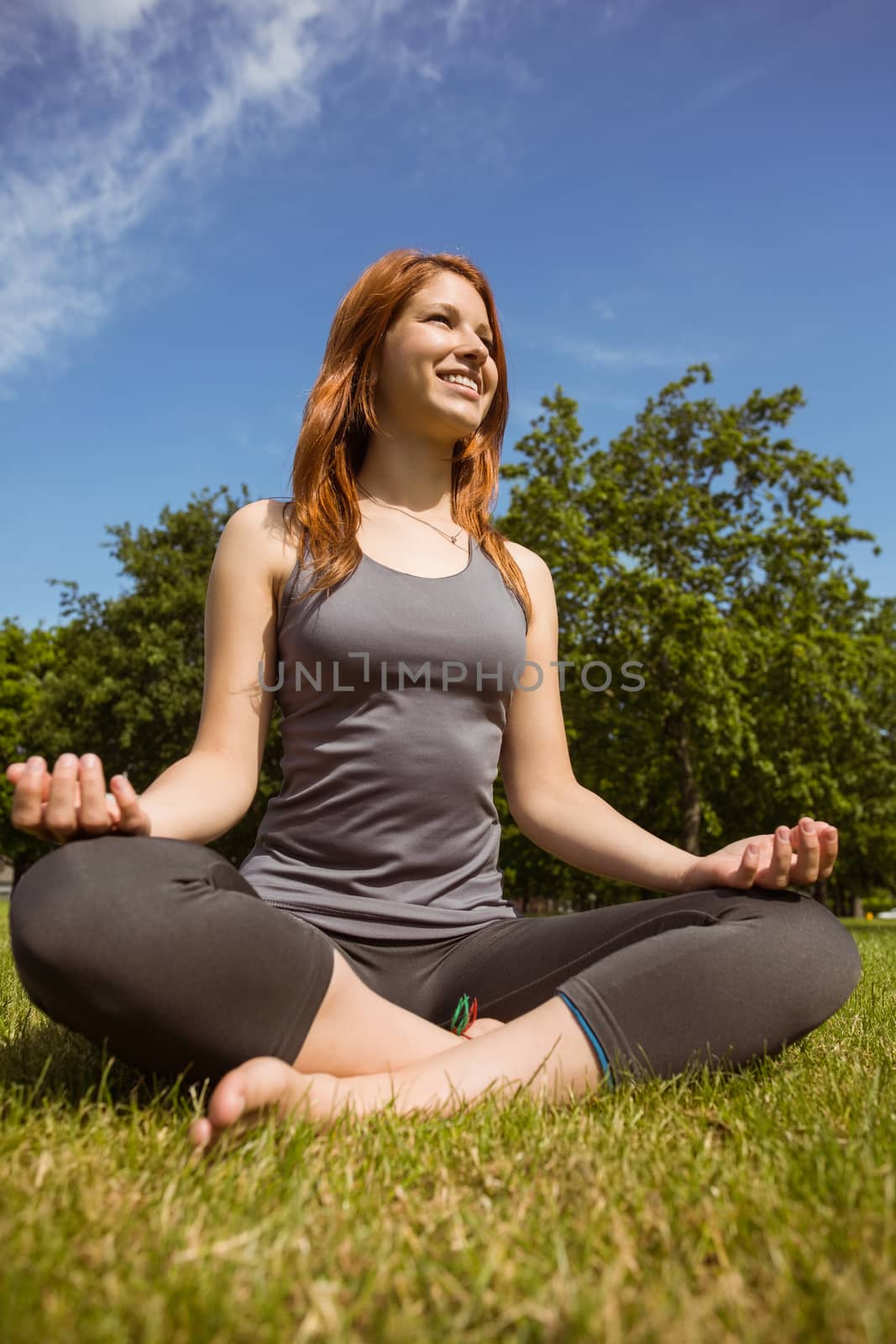 Portrait of a pretty redhead relaxing in lotus pose by Wavebreakmedia