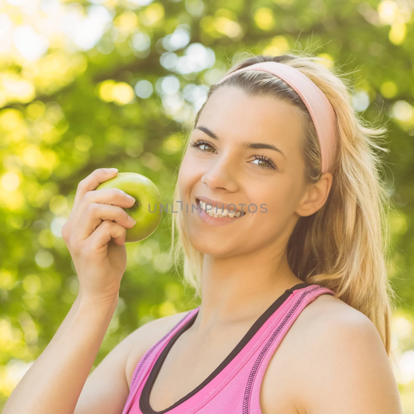 Fit blonde holding green apple on a sunny day