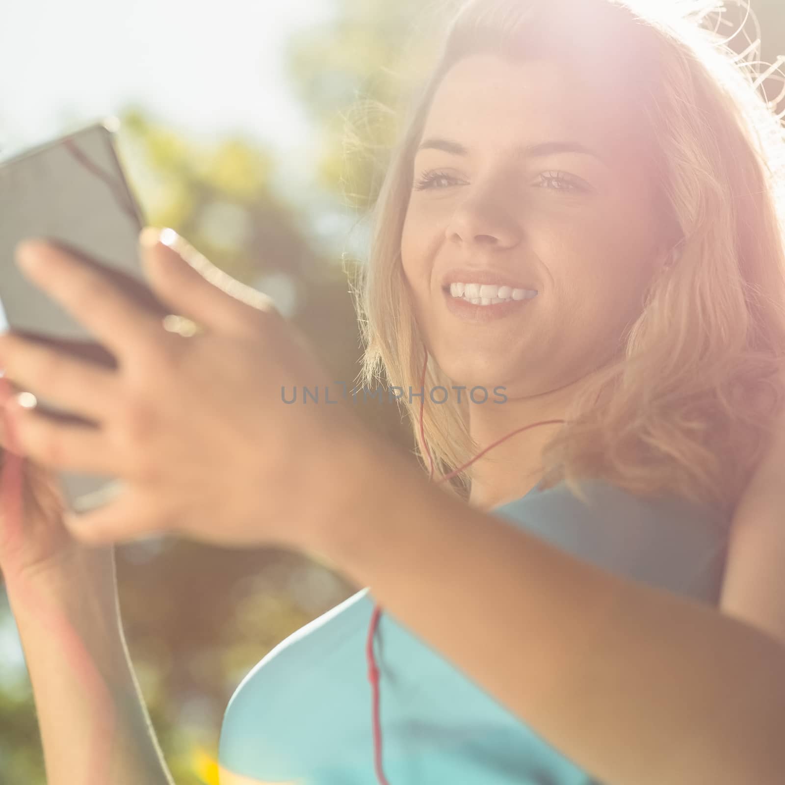 Fit blonde texting on her smartphone on a sunny day