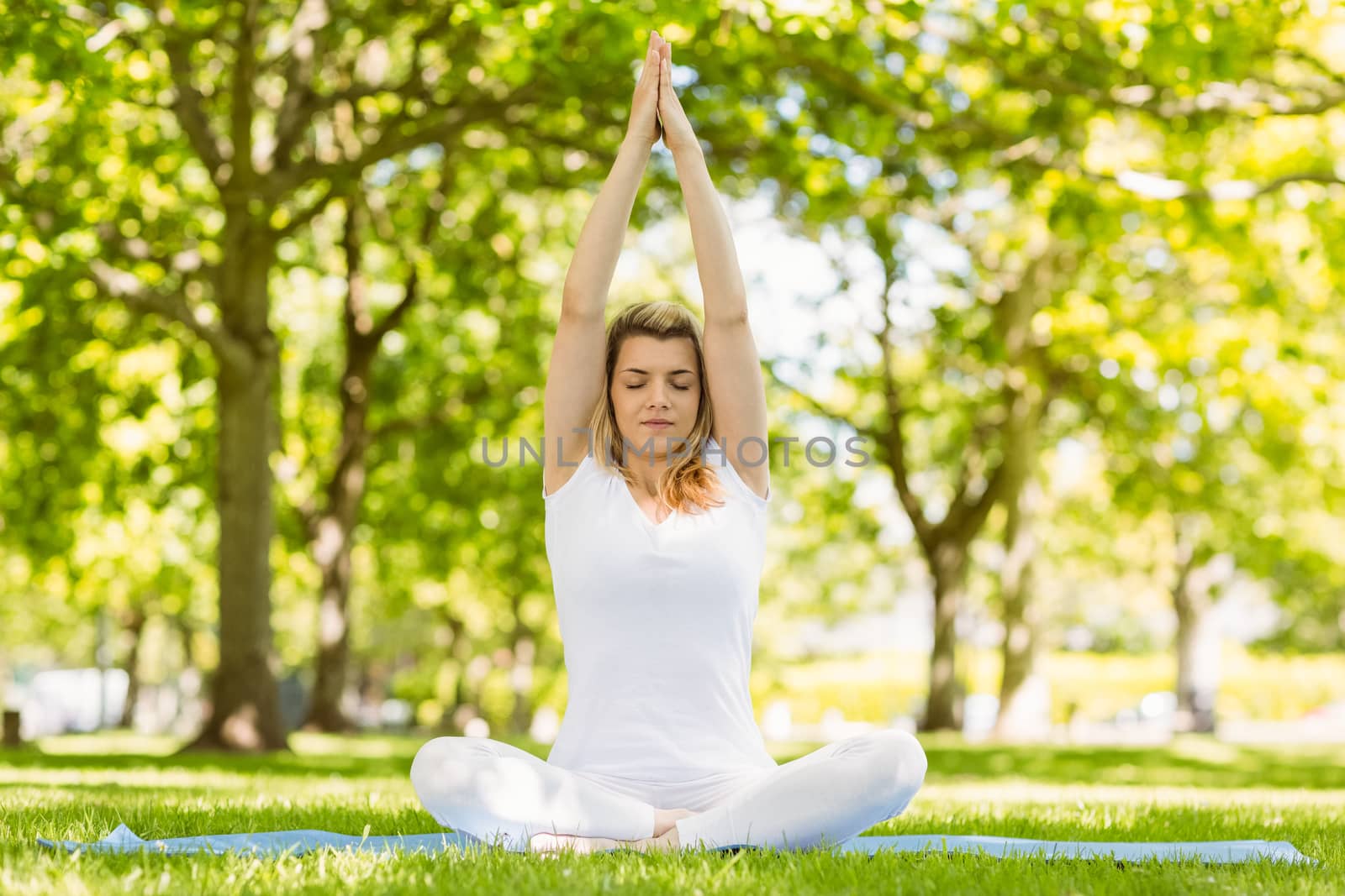 Fit blonde sitting in lotus pose in the park on a sunny day