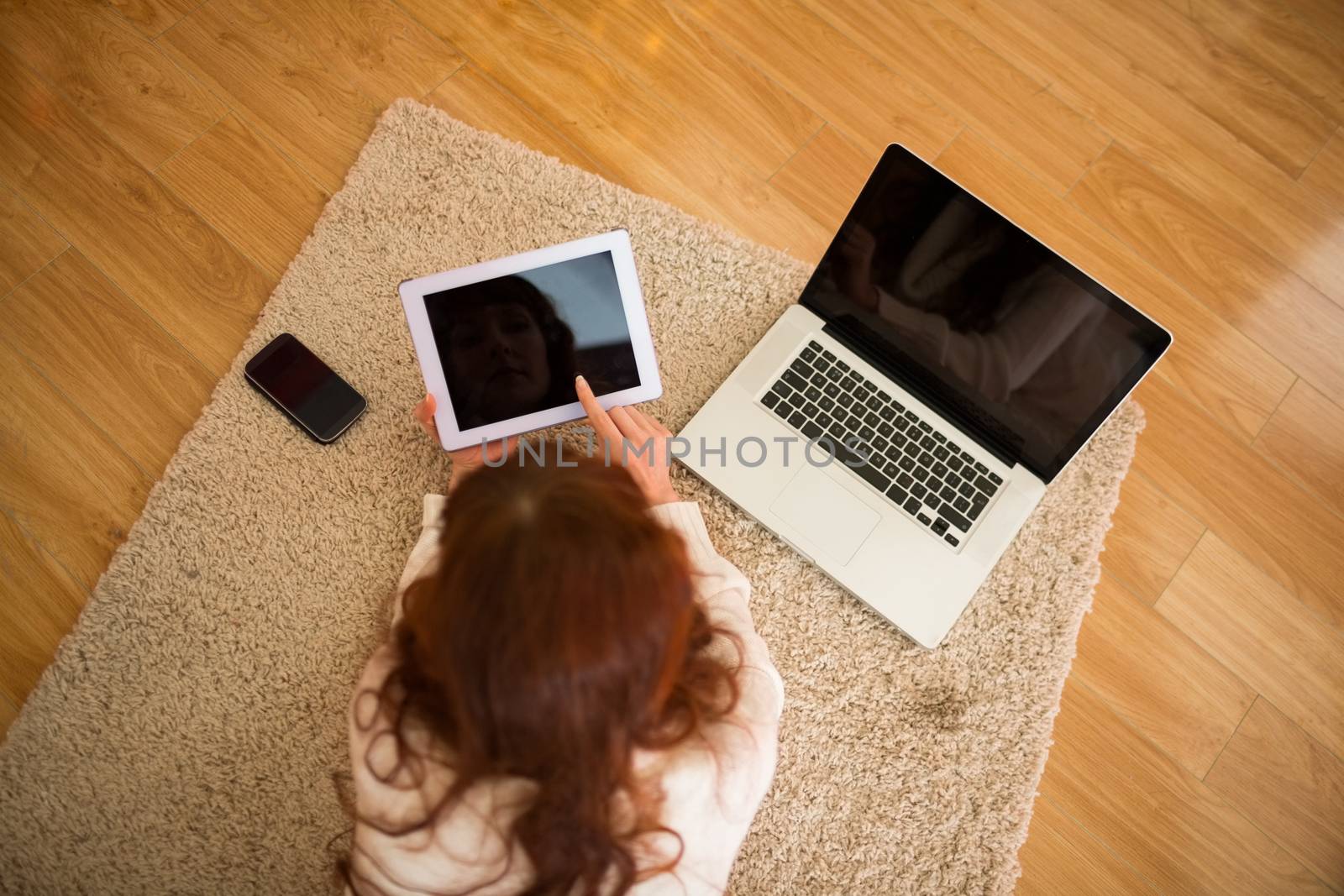 Pretty woman lying on floor using technology at Chritmas at home in the living room