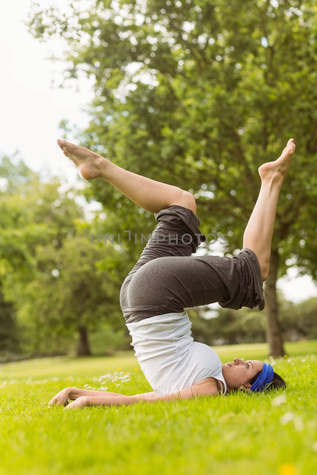 Concentrated brown hair doing yoga on grass by Wavebreakmedia