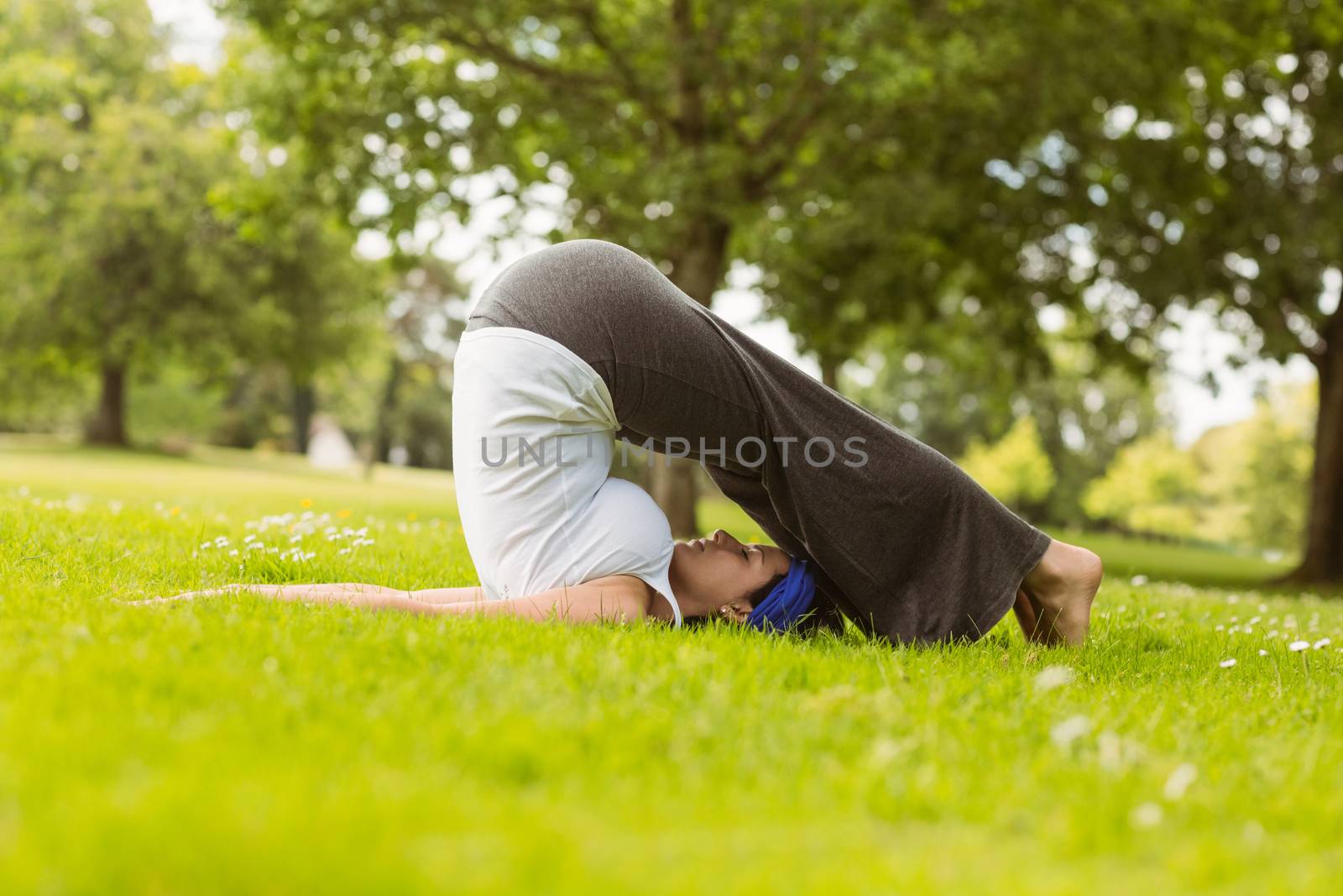 Brown hair doing yoga on grass in the park