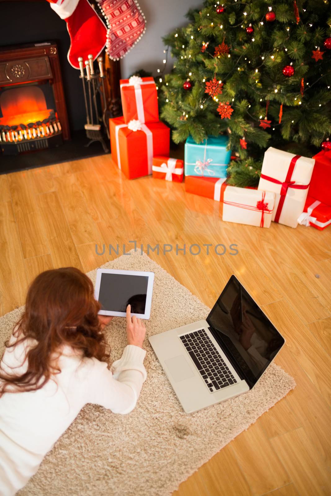 Pretty woman lying on floor using technology at Chritmas at home in the living room
